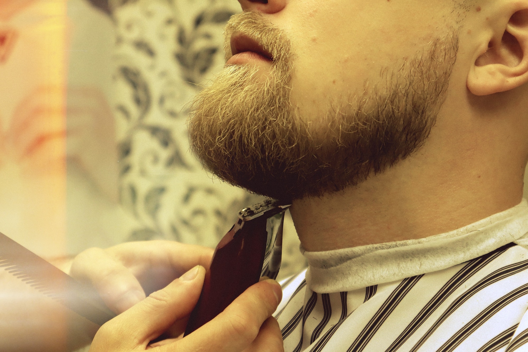 Barber shaves beard of client man on chair Barbershop. Beard Haircut.